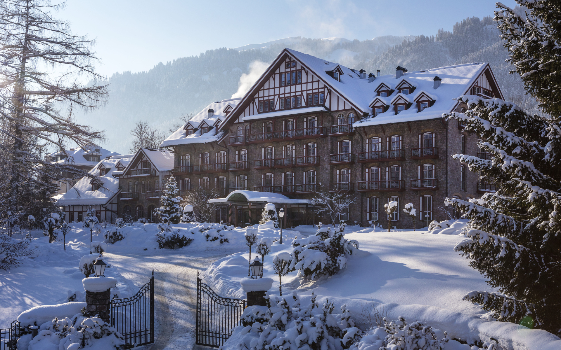 Snow-covered Grand Hotel with a landscaped entrance and mountains in the background
