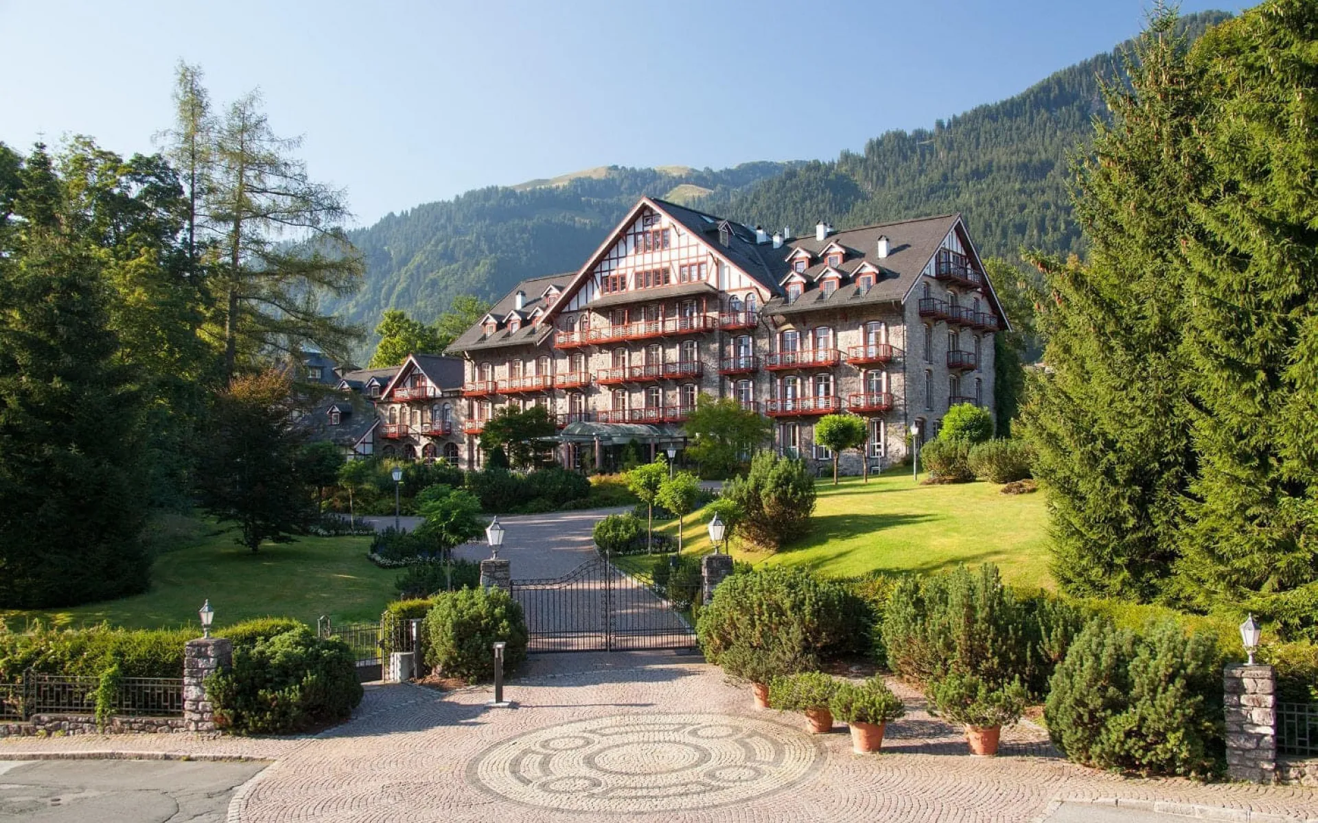Grand Hotel Kitzbühel with lush greenery and mountains in the background